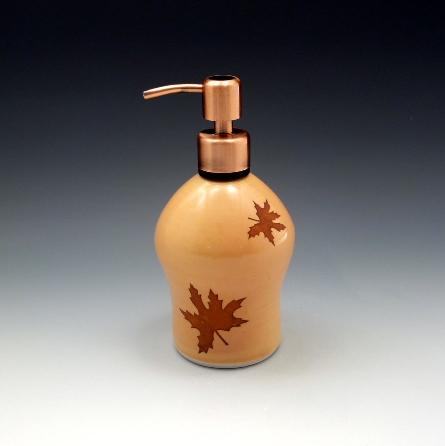 Amber glazed porcelain soap dispenser with leaves falling and brushed copper pump